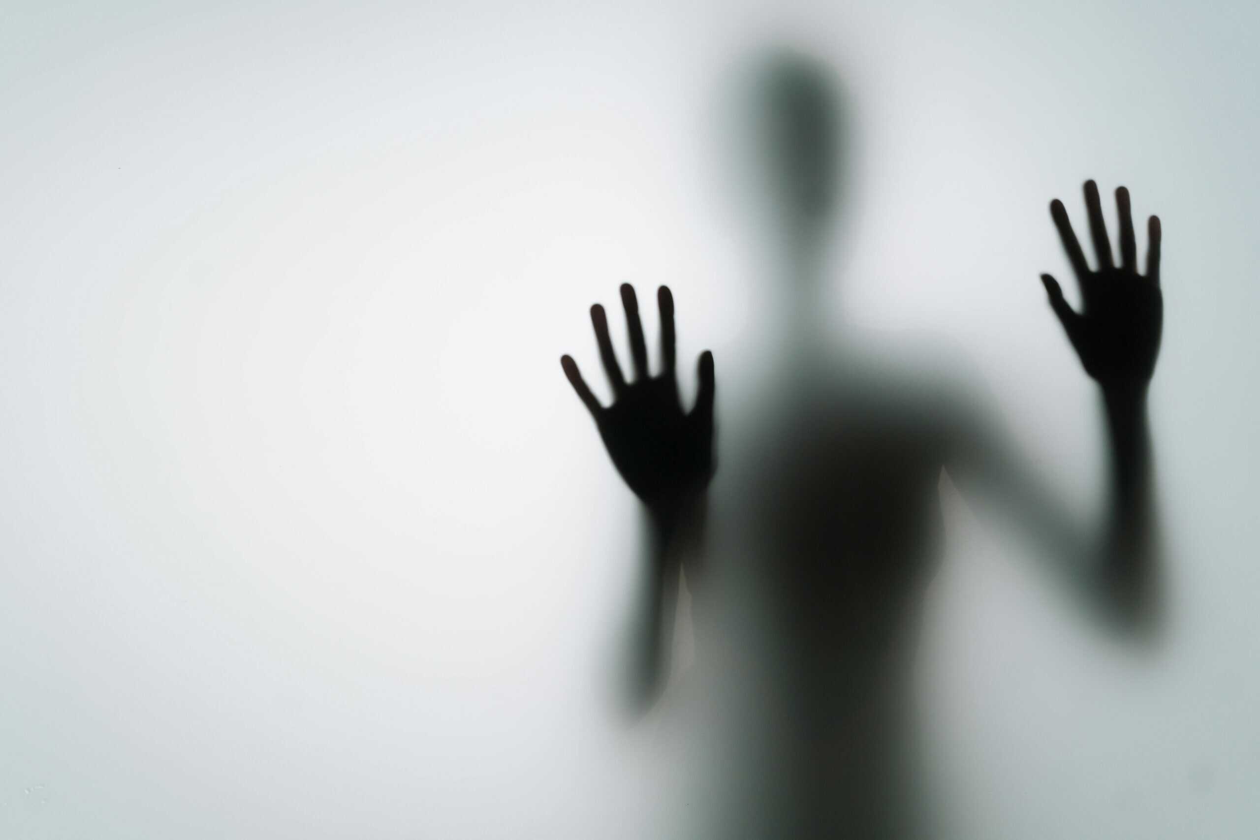 Silhouette of a person with an outstretched hand pressing against a foggy, opaque surface, creating an ethereal effect that captures the feeling of being stuck in search of truth.